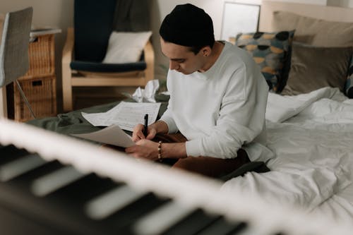 Man in White Robe Writing on White Paper